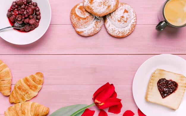 Pane tostato con marmellata a forma di cuore con tulipano, bacche e panini