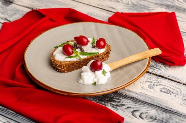 pane tostato con panna acida e corniolo su grigio