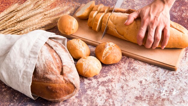 Panettiere dell'angolo alto che affetta pagnotta di pane