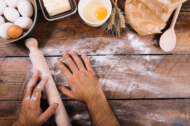 Panettiere spolverare con farina sul tavolo in legno con ingredienti cotti