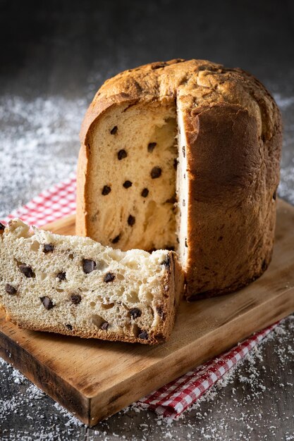 Panettone natalizio tradizionale con cravatta rossa e ornamenti natalizi su tavola di legno