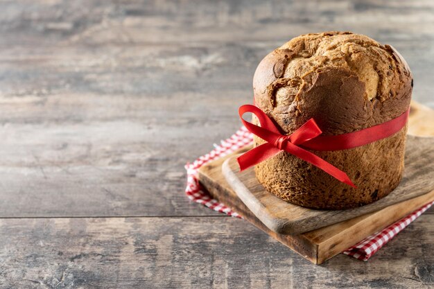 Panettone natalizio tradizionale con cravatta rossa su tavola di legno