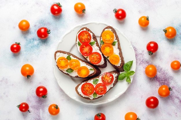 Panini aperti con ricotta, pomodorini e basilico.