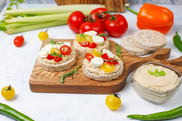 Panini aperti di torte di riso con hummus, verdure e uovo di quaglia, colazione sana o pranzo