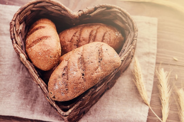 Panini caldi appena sfornati in un cesto a forma di cuore. Foto ravvicinata di prodotti a base di pane appena sfornati.