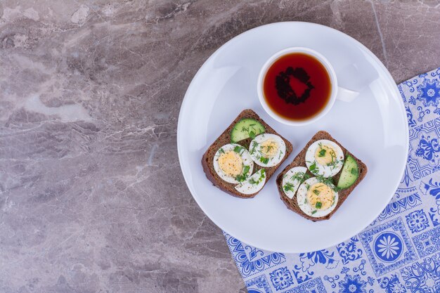 Panini con uova sode ed erbe aromatiche con una tazza di tè.