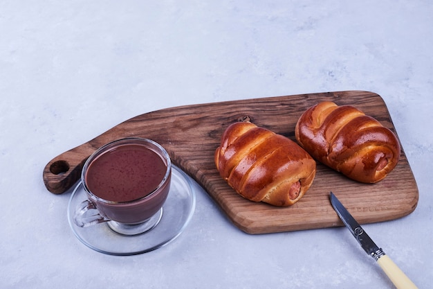 Panini dolci su una tavola di legno con una tazza di cioccolata calda sul blu