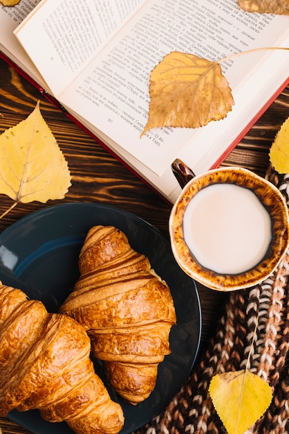 Panini e latte del primo piano vicino al libro e alle foglie