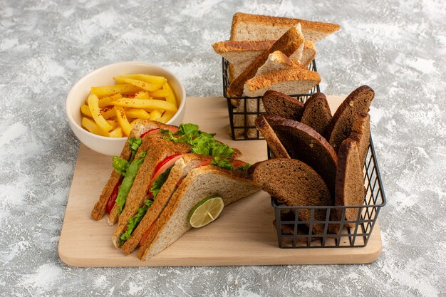 panini e patatine fritte insieme a diversi tipi di pane su grigio