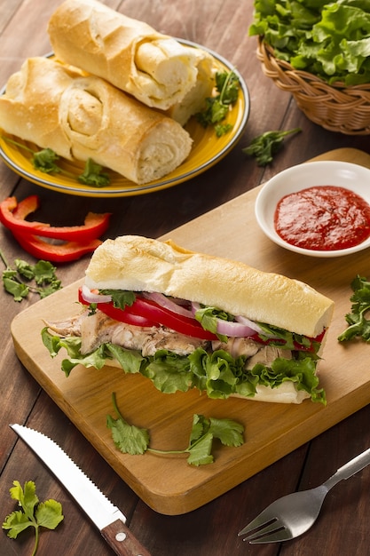 Panino baguette con cipolle, peperoni, lattuga e pollo cotto accompagnato da ketchup