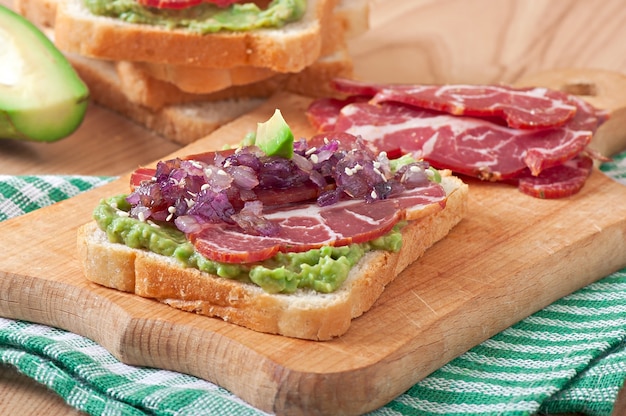 Panino con prosciutto, salsa di avocado e cipolle caramellate