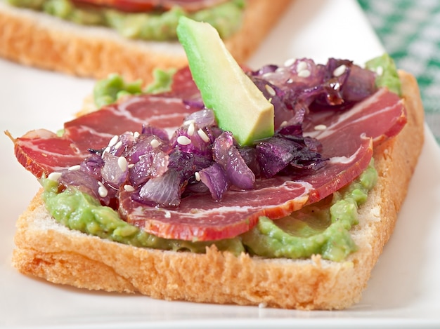 Panino con prosciutto, salsa di avocado e cipolle caramellate