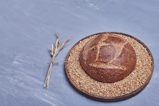 Panino di pane rotondo fatto a mano su un piatto di legno.
