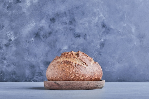 Panino di pane tondo fatto a mano sul piatto di grano, vista laterale.