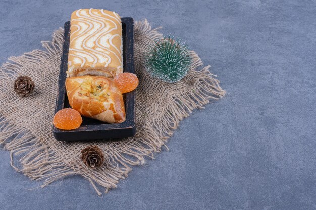 Panino dolce con caramelle di gelatina e pigne su tela di sacco