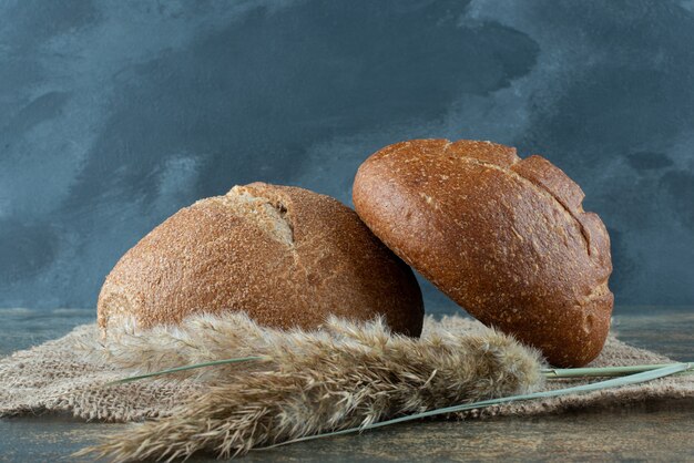 Panino marrone fresco due con grano su tela di sacco