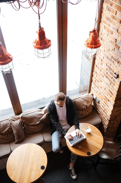 Pantaloni a vita bassa barbuti che utilizzano computer portatile nel caffè