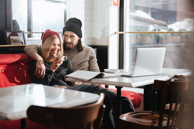 Pantaloni a vita bassa che si siedono con il computer portatile in caffè