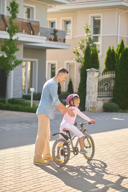 Papà aiuta sua figlia a imparare ad andare in bicicletta