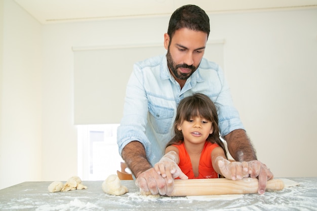 Papà bello che insegna alla figlia a cuocere.