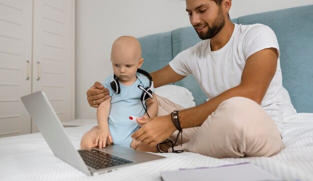 Papà che lavora al laptop da casa durante la quarantena con il bambino