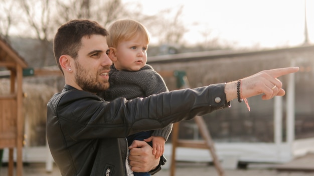 Papà che punta e tiene suo figlio nel parco giochi