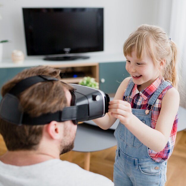 Papà d&#39;aiuto della ragazza allegra con l&#39;auricolare di VR