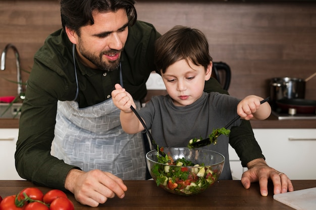 Papà e figlio a casa che producono insalata