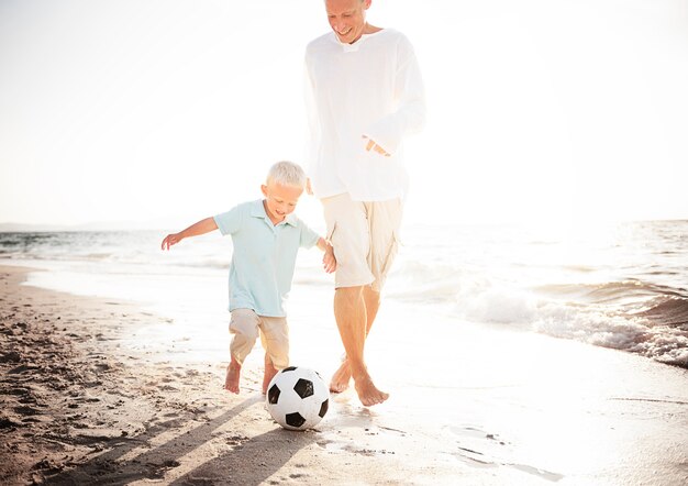 Papà e figlio giocano a calcio sulla spiaggia