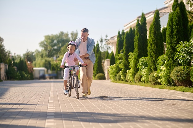 Papà in bicicletta con sua figlia seduta su di essa