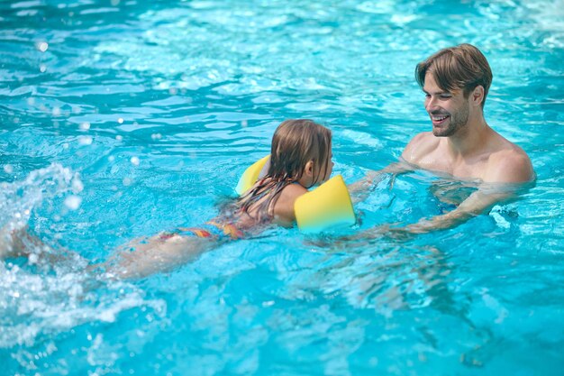 Papà insegna a sua figlia a nuotare in una piscina