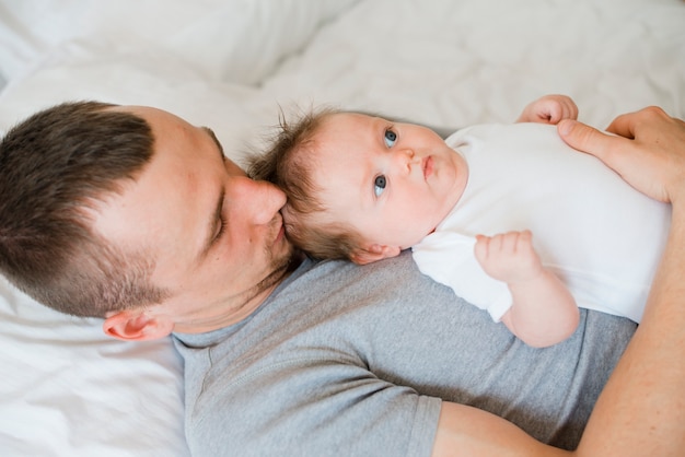 Papà sdraiato sul letto e abbracciando bambino