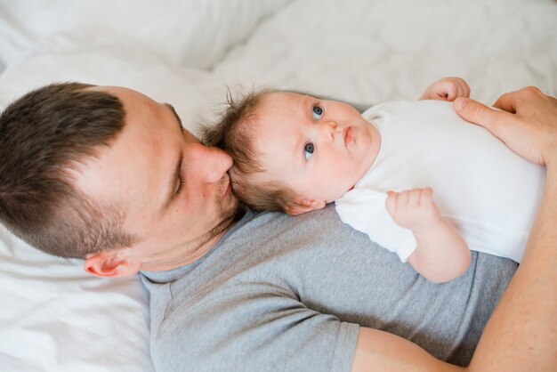 Papà sdraiato sul letto e abbracciando bambino