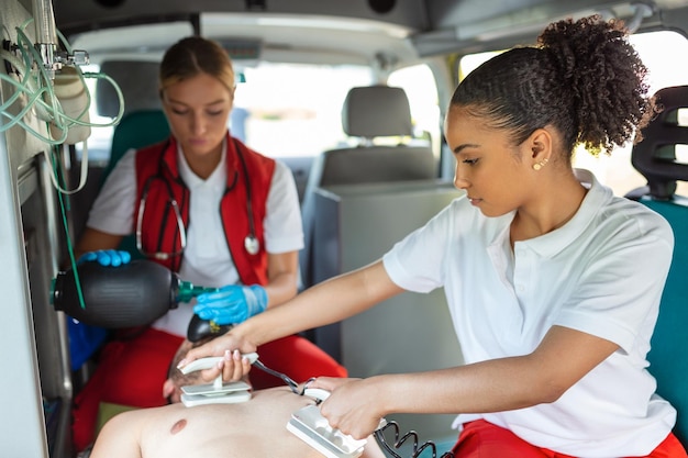 Paramedico che utilizza un defibrillatore DAE per condurre una rianimazione cardiopolmonare di base Assistente per le emergenze Mettere i rianimatori manuali in silicone in un'ambulanza