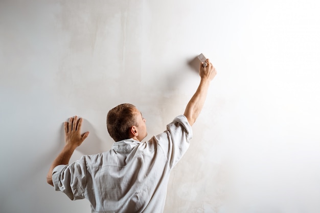 Parete della pittura del lavoratore con la spazzola nel colore bianco.