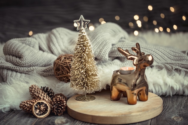 Parete festiva di Natale con cervi giocattolo con scatola regalo e albero di Natale, parete sfocata con luci dorate sul tavolo di ponte di legno