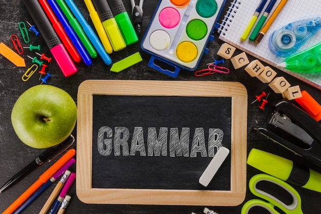 Parola di grammatica sulla lavagna con materiale scolastico