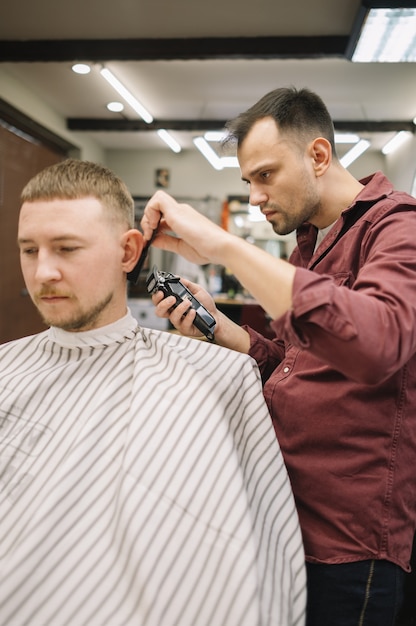 Parrucchiere che dà un taglio di capelli al negozio di barbiere