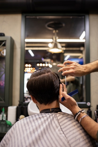Parrucchiere che taglia i capelli di un uomo dal barbiere