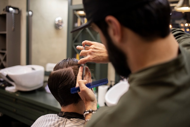 Parrucchiere che taglia i capelli di un uomo dal barbiere