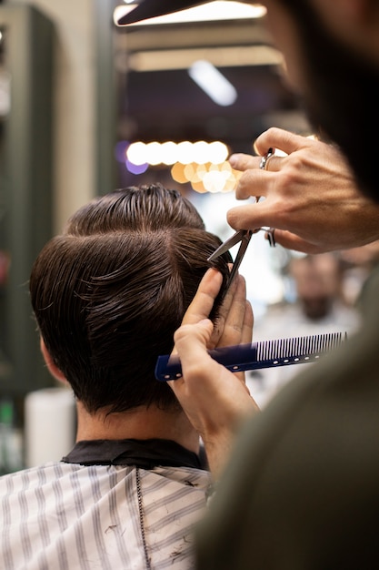 Parrucchiere che taglia i capelli di un uomo dal barbiere