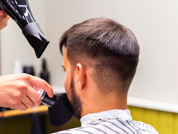 Parrucchiere con asciugacapelli e pennello da barba