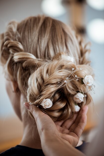 Parrucchiere femminile che fa acconciatura alla donna bionda nel salone di bellezza