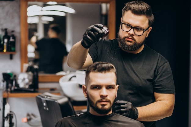 Parrucchiere in un negozio di barbiere che disegna i capelli di un cliente