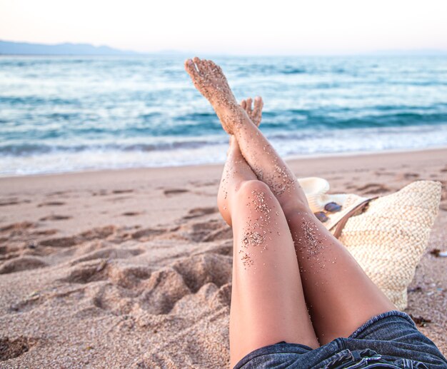 Parte del corpo. Piedi femminili nella sabbia sulla spiaggia in riva al mare si chiudono.