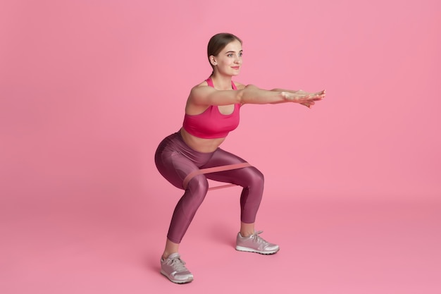 Parte inferiore del corpo. Bella giovane atleta femminile che pratica in studio, ritratto rosa monocromatico.