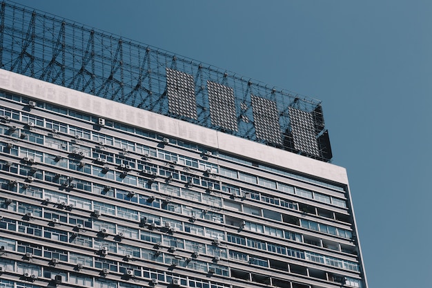 Parte superiore di un vecchio condominio con proiettili di metallo sul tetto e cielo blu chiaro