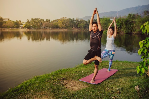 Partner di yoga bilanciati accanto al lago