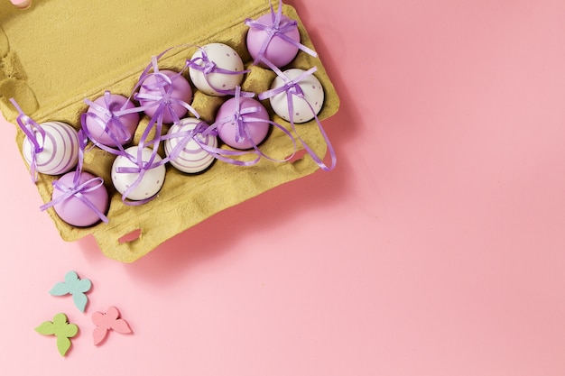 Pasqua o primavera, concetto di alimenti. Uova fresche in scatola per uova sul colore rosa sfondo pastello. Vista dall&#39;alto.