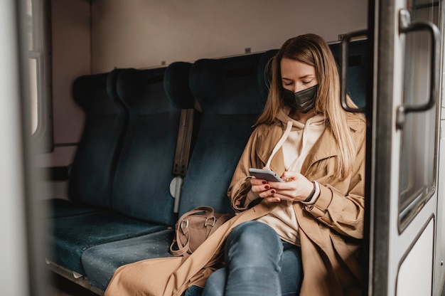 Passeggero femminile seduto in un treno e indossa una maschera medica